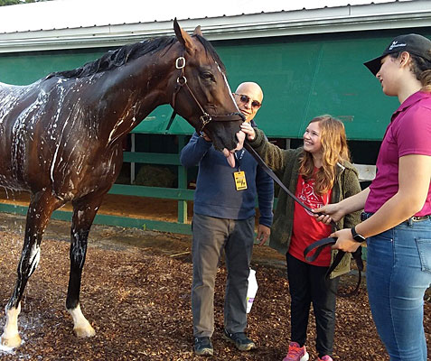 Eva gets to pet her hero War of Will as trainer Mark Casse looks on